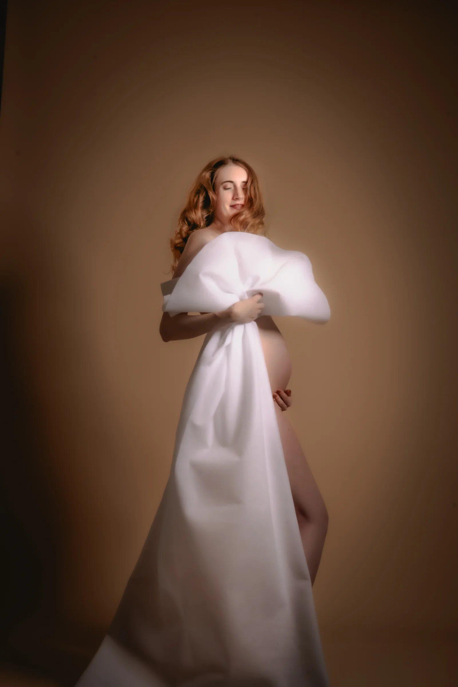 Full-length maternity portrait in a flowing white dress