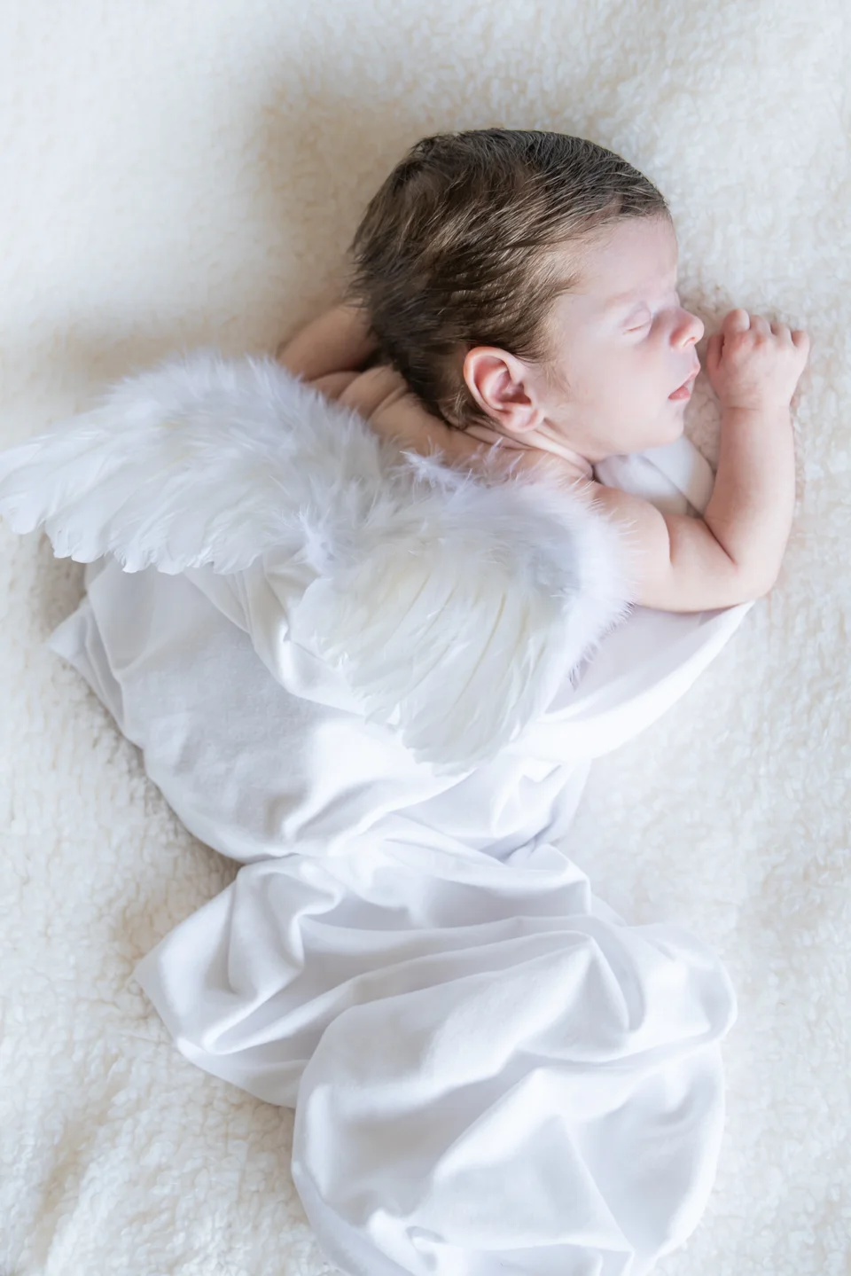 Sleeping newborn wearing a white outfit