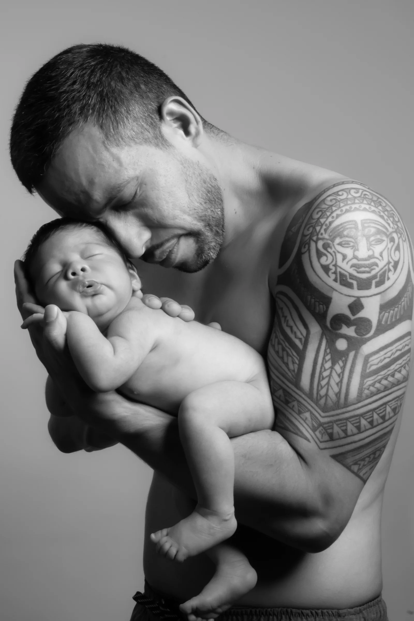 Black-and-white portrait of a father cuddling his newborn