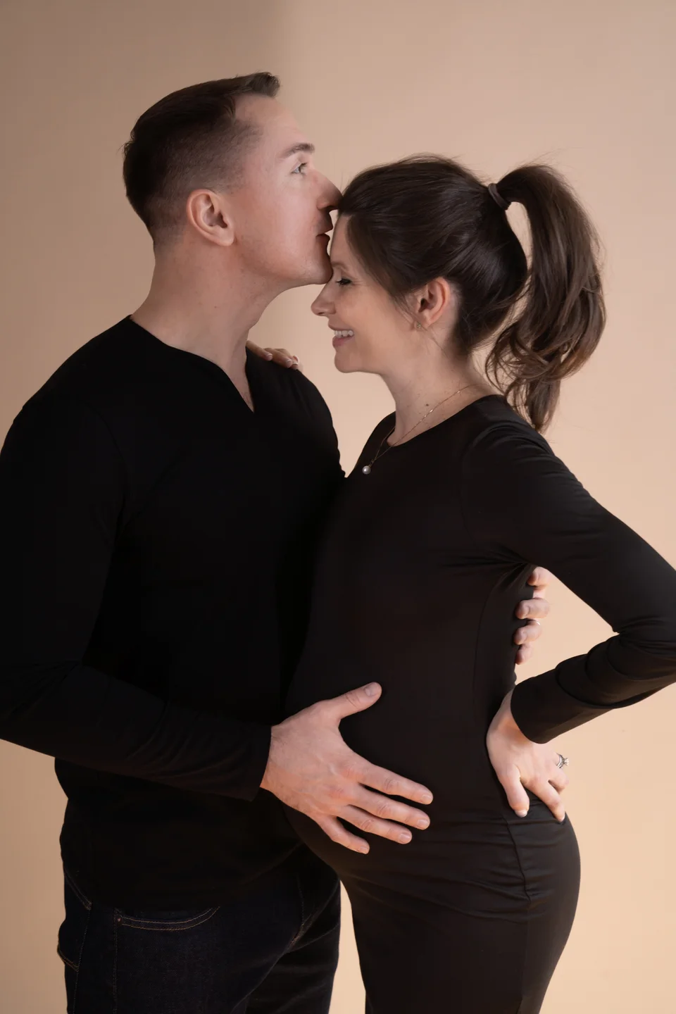 Couple touching foreheads with hands on a pregnant belly
