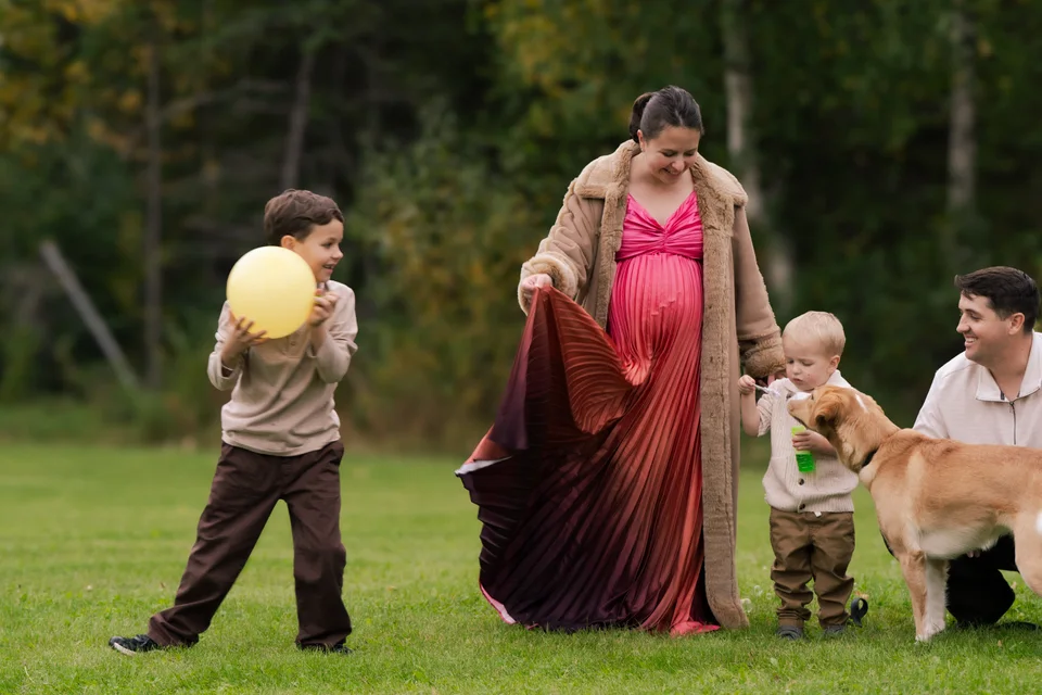 Family maternity portrait outdoors among green trees