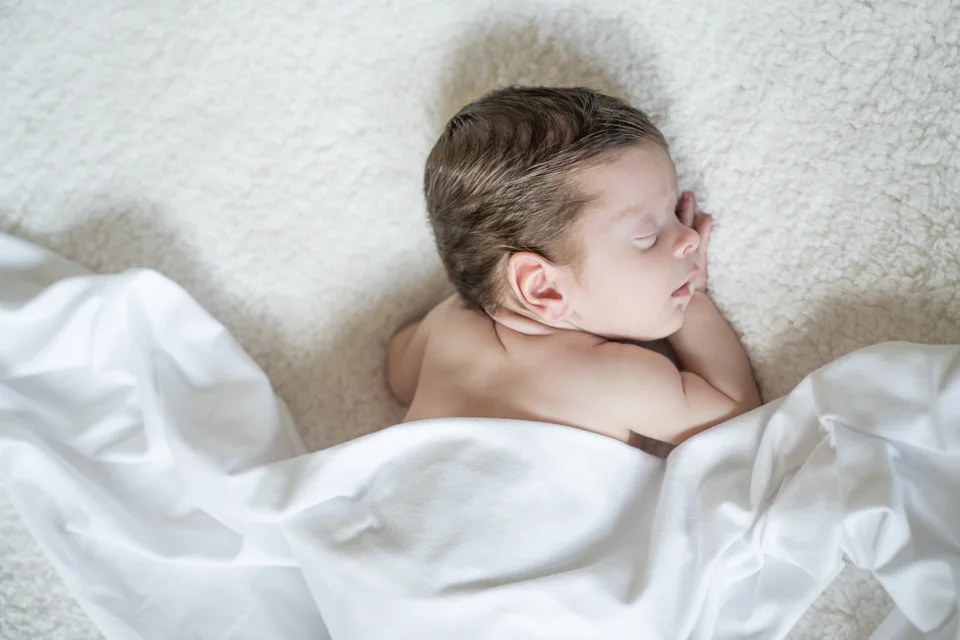 Sleeping newborn in profile on a white blanket