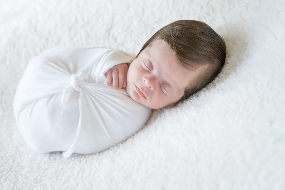 Sleeping newborn wrapped in a white blanket