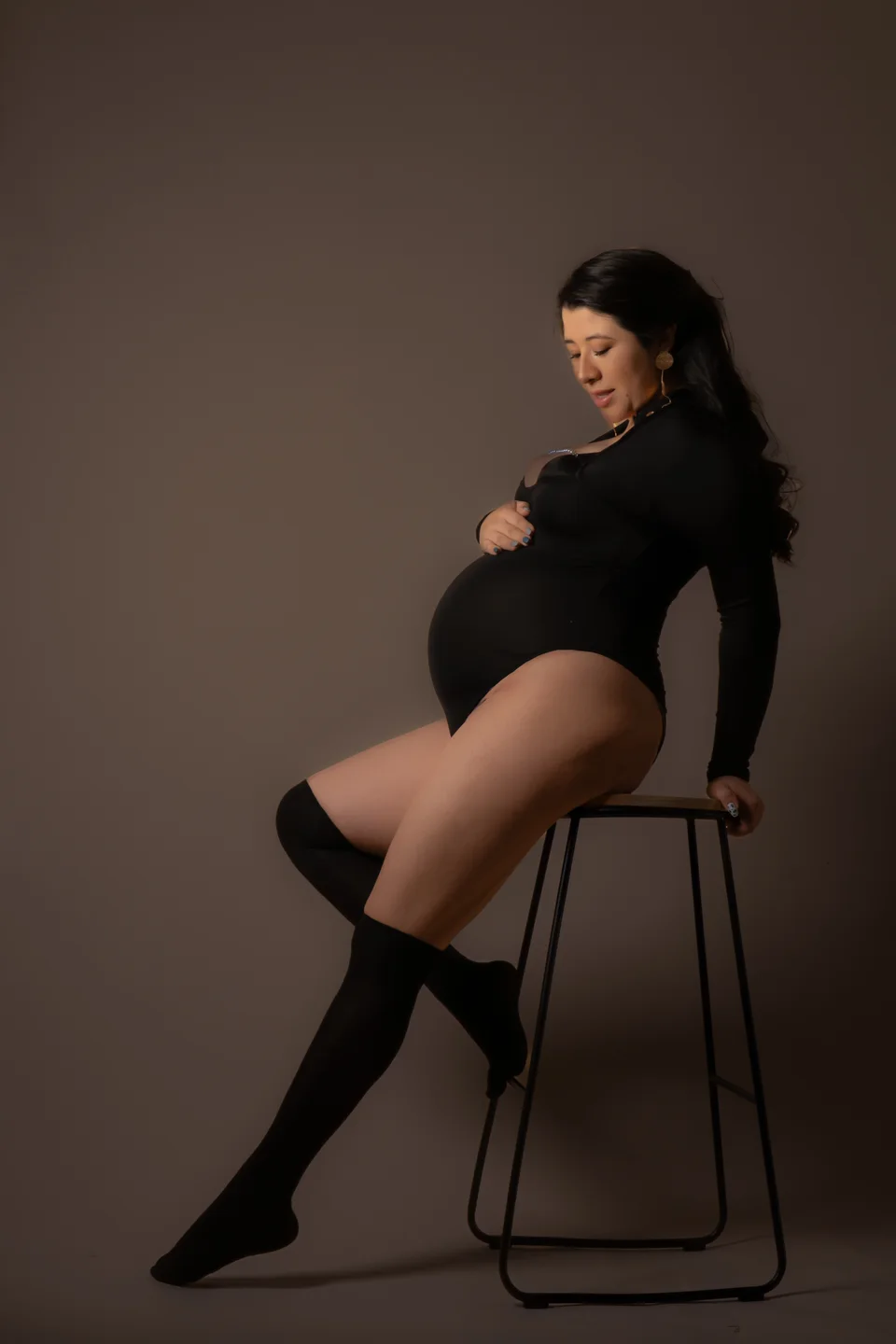 Seated maternity portrait in black clothing and knee-high boots