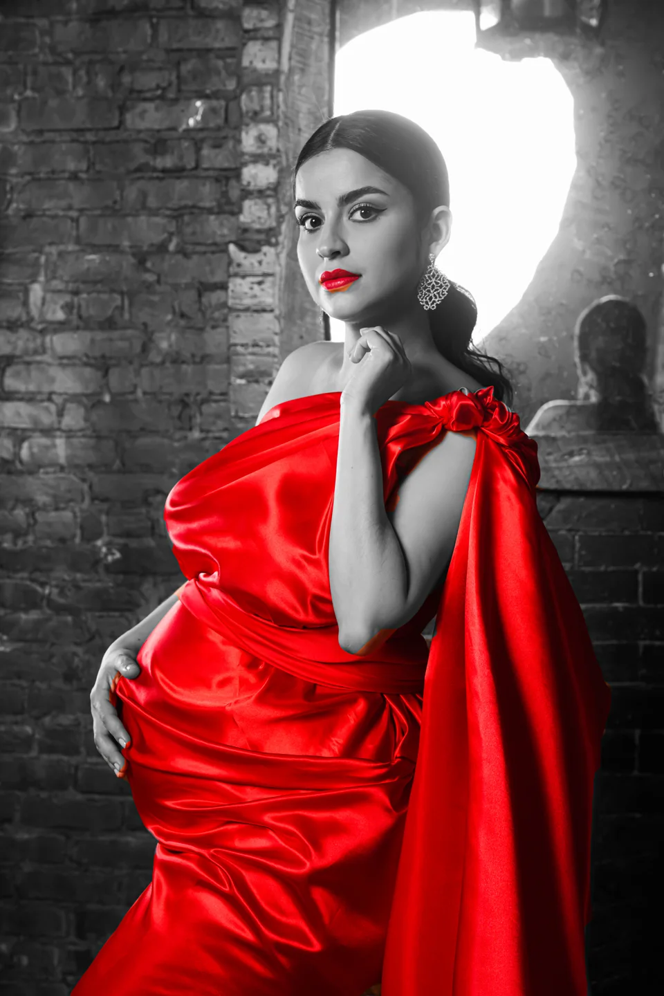 Portrait in a vivid red gown against a monochrome brick backdrop