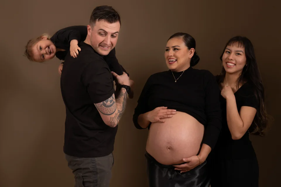 Family maternity portrait in black clothing against a warm backdrop