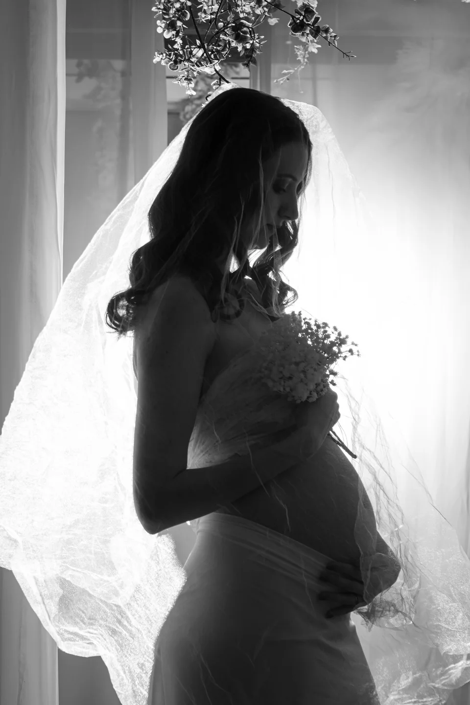 Black-and-white maternity silhouette beside a window