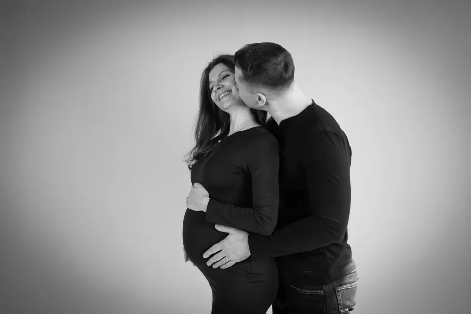 Black-and-white couple portrait with a gentle forehead kiss