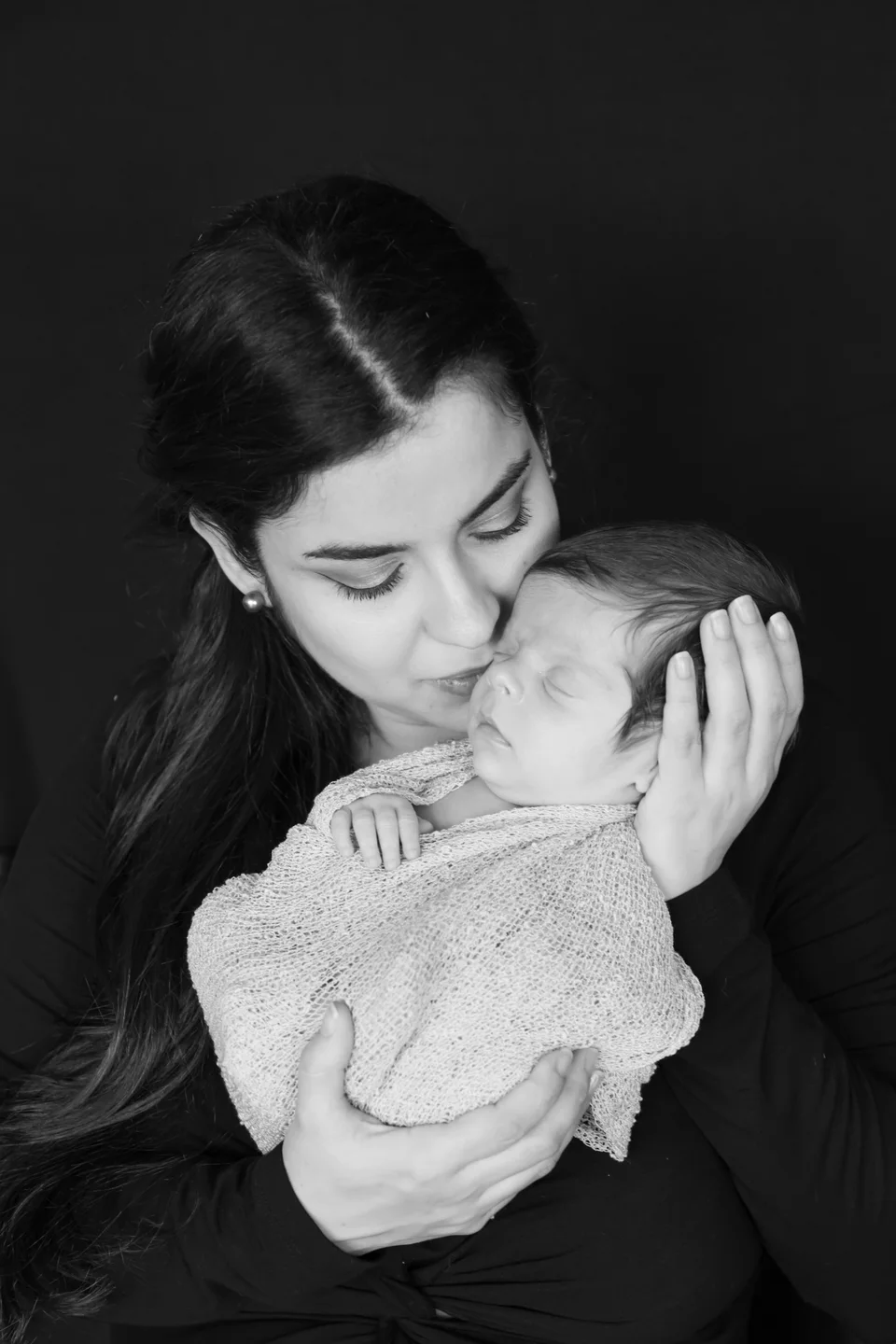Black-and-white portrait of a mother holding her newborn close