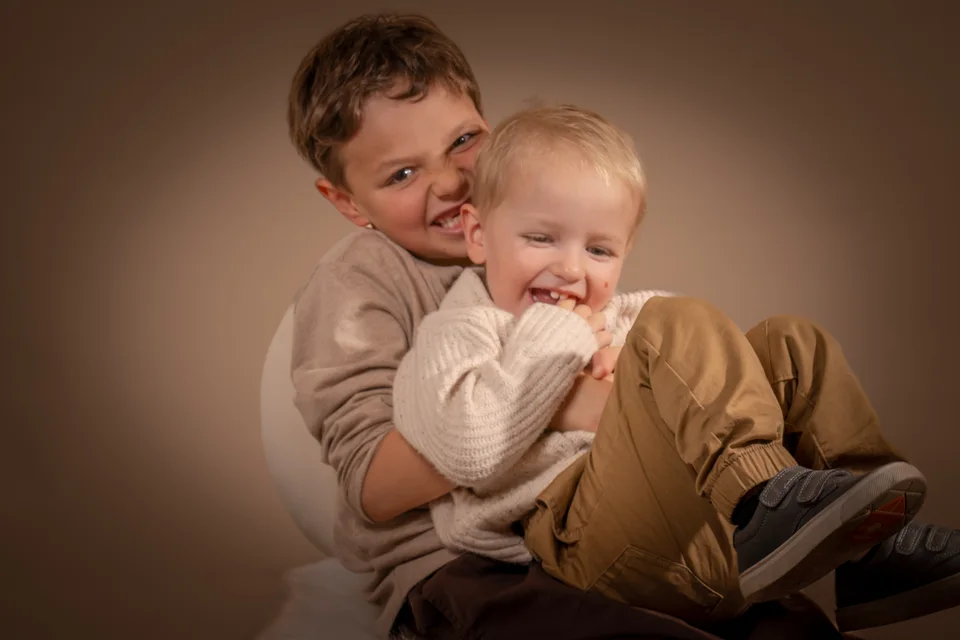 Portrait of two brothers embracing against a warm backdrop