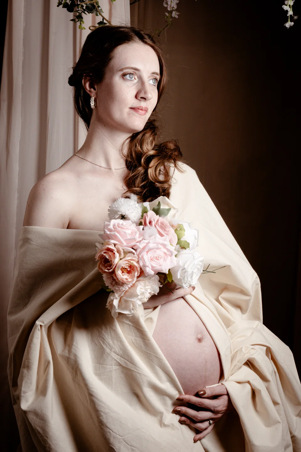 Maternity portrait with satin fabric and a floral bouquet