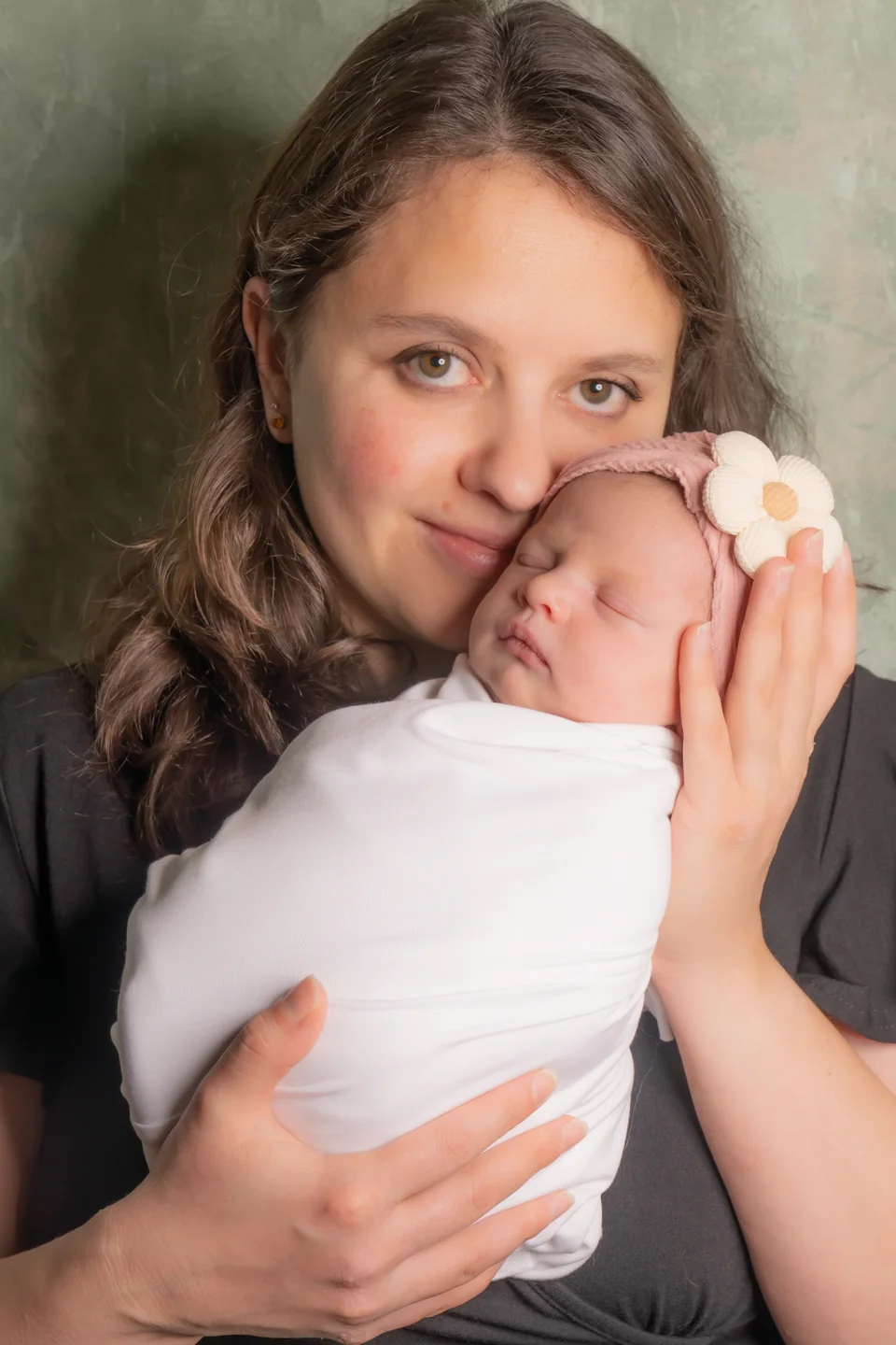 Older sibling cuddling a swaddled newborn