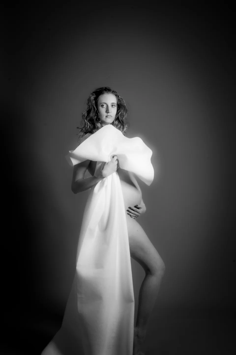 Black-and-white maternity portrait with a long white cape