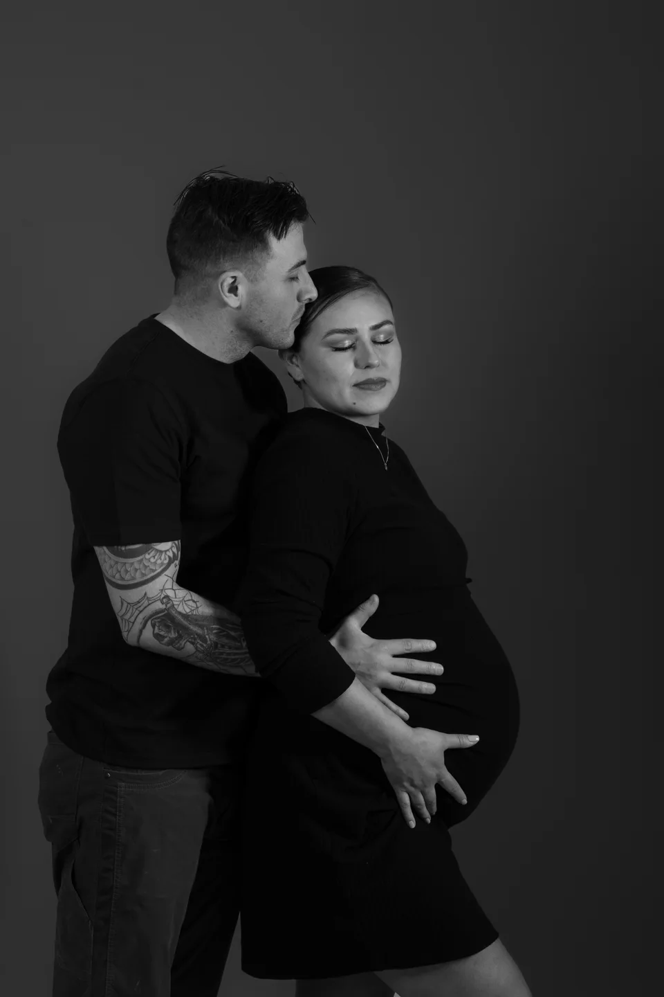 Black-and-white portrait of a couple embracing during pregnancy