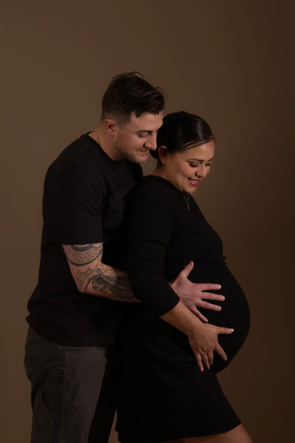 Couple looking down together at a pregnant belly