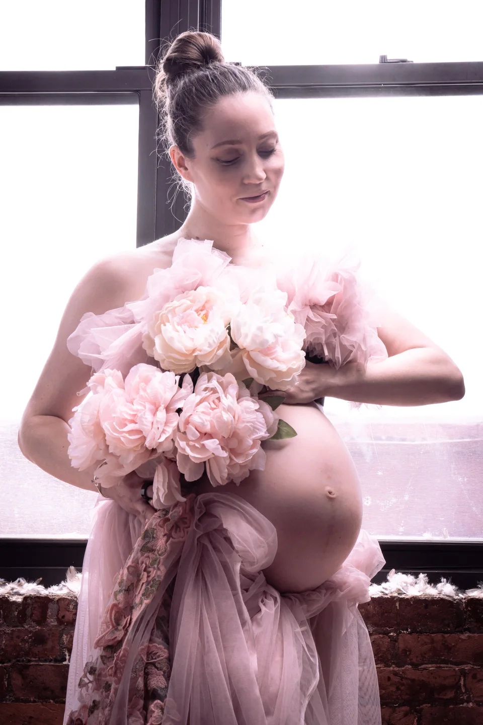 Maternity portrait with a pink bouquet and ruffled sleeves