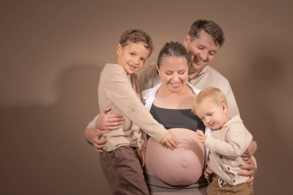 Parents embracing their children around a pregnant belly