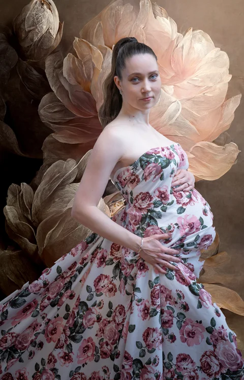 Maternity portrait in a floral gown against oversized flowers